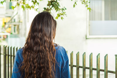 Rear view of woman standing against fence