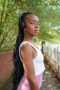 Portrait of young woman standing against trees