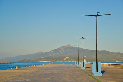 Street by sea against clear blue sky