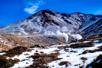 Scenic view of snowcapped mountains against blue sky