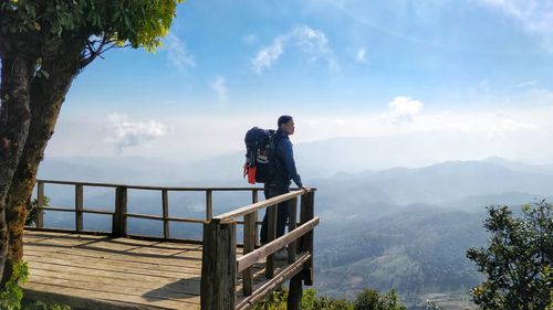 Side view of men looking at mountains against sky