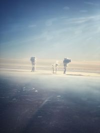 People on snow covered land against sky