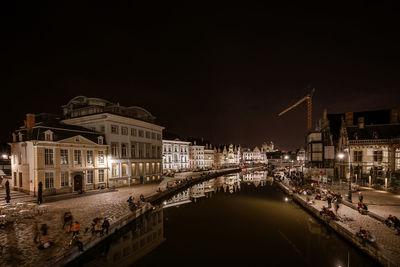 People by canal in city at night