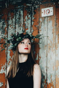 Beautiful young woman standing against old fence