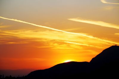 Silhouette mountain against dramatic sky during sunset