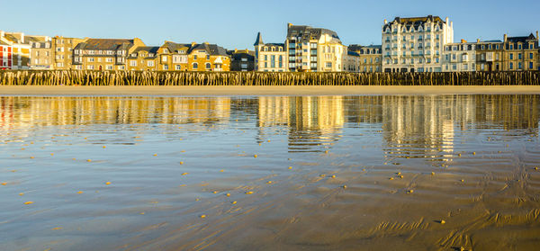 Reflection of buildings in water against clear sky