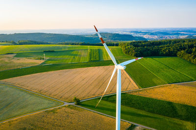 High-angle view of wind turbine in rural area at sunset