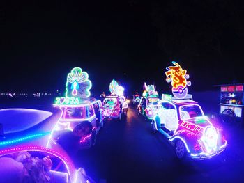 Illuminated carousel in amusement park against sky at night