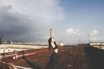 Woman taking selfie on bridge against sky