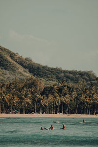 People swimming in sea against sky