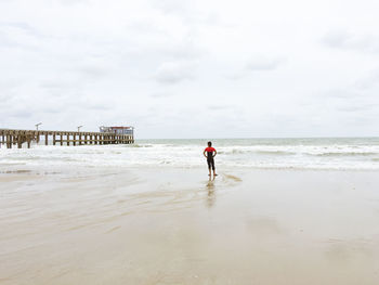 Full length of man walking on beach against sky