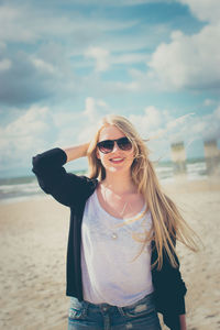 Portrait of smiling young woman wearing sunglasses at beach