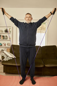 Senior man exercising with resistance band at home