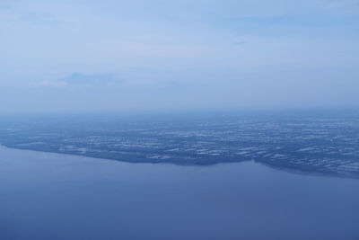 Aerial view of sea and cityscape against sky