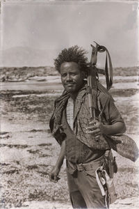 Portrait of man holding camera while standing on beach