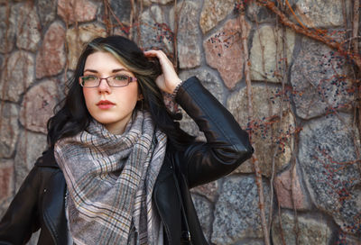 Portrait of young woman standing against rock