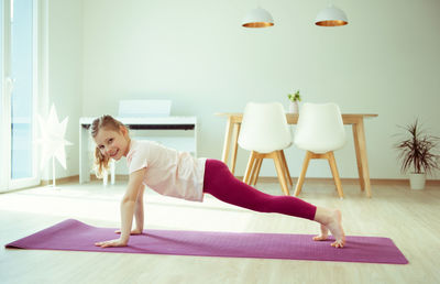 Girl practicing yoga on mat at home