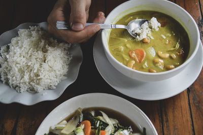 Midsection of person having food in bowl on table