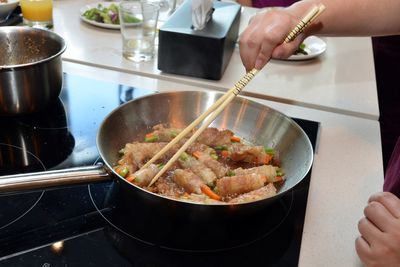 Cropped image of hand taking food from frying pan