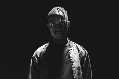 Portrait of young man standing against sky at night