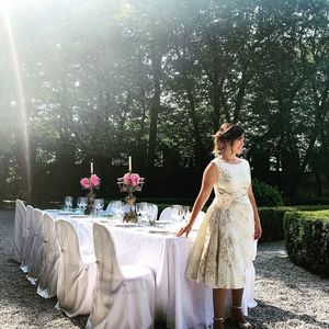 Woman standing by flowering plants against trees