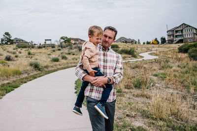 Dad carrying young son on a walking trail