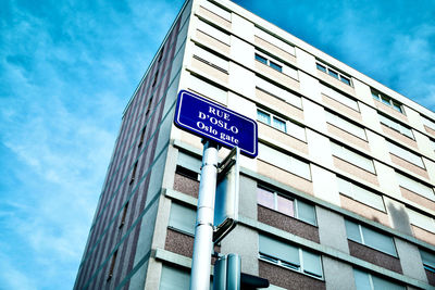 Low angle view of road sign by building against sky