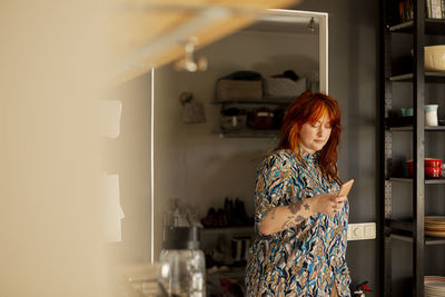 Woman in kitchen using cell phone