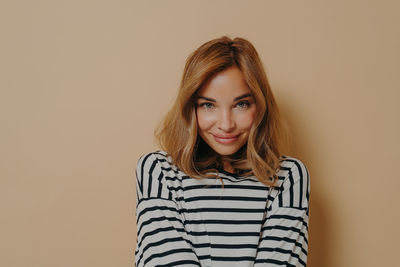 Portrait of young woman standing against yellow background