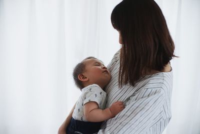 Side view of mother and baby boy at home