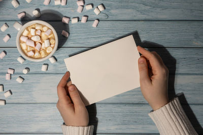 Cropped hands of woman holding book on table