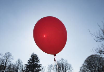 Red balloon and blue sky background with sun, symbol for joy and happiness