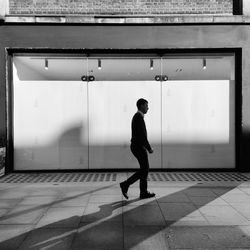 Full length side view of man walking on footpath