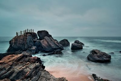 Scenic view of rock formations in sea against sky