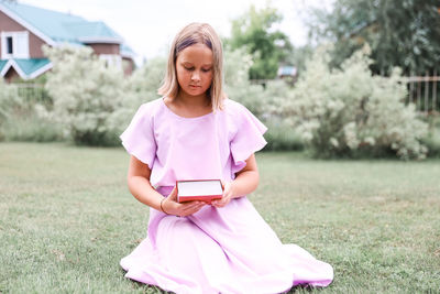 Portrait of young woman using mobile phone while sitting on field