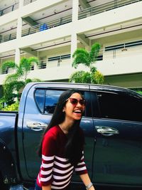 Young woman smiling while standing by car