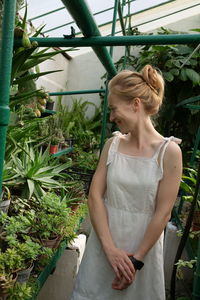 A woman standing in front of a green plant