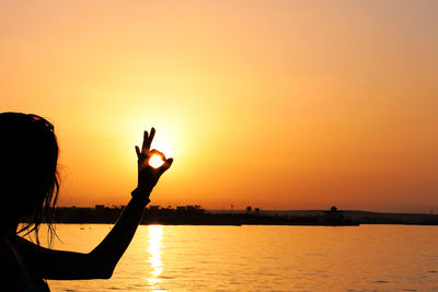 Optical illusion of woman holding sun