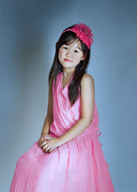 Portrait of teenage girl standing against pink background