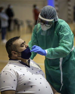 Doctor wearing protective suit examining patient wearing mask