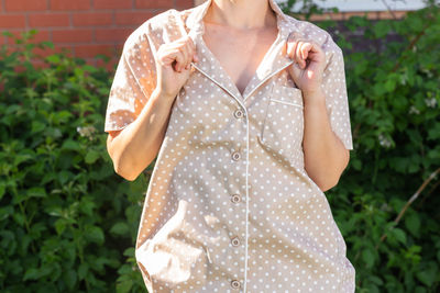 Midsection of woman standing against plants