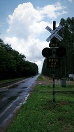 Road passing through field against cloudy sky