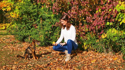 Woman with dog sitting on plants