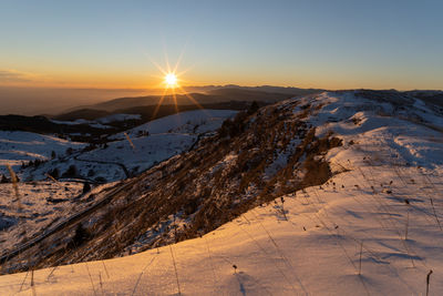 Scenic view of snowcapped mountains against sky during sunset