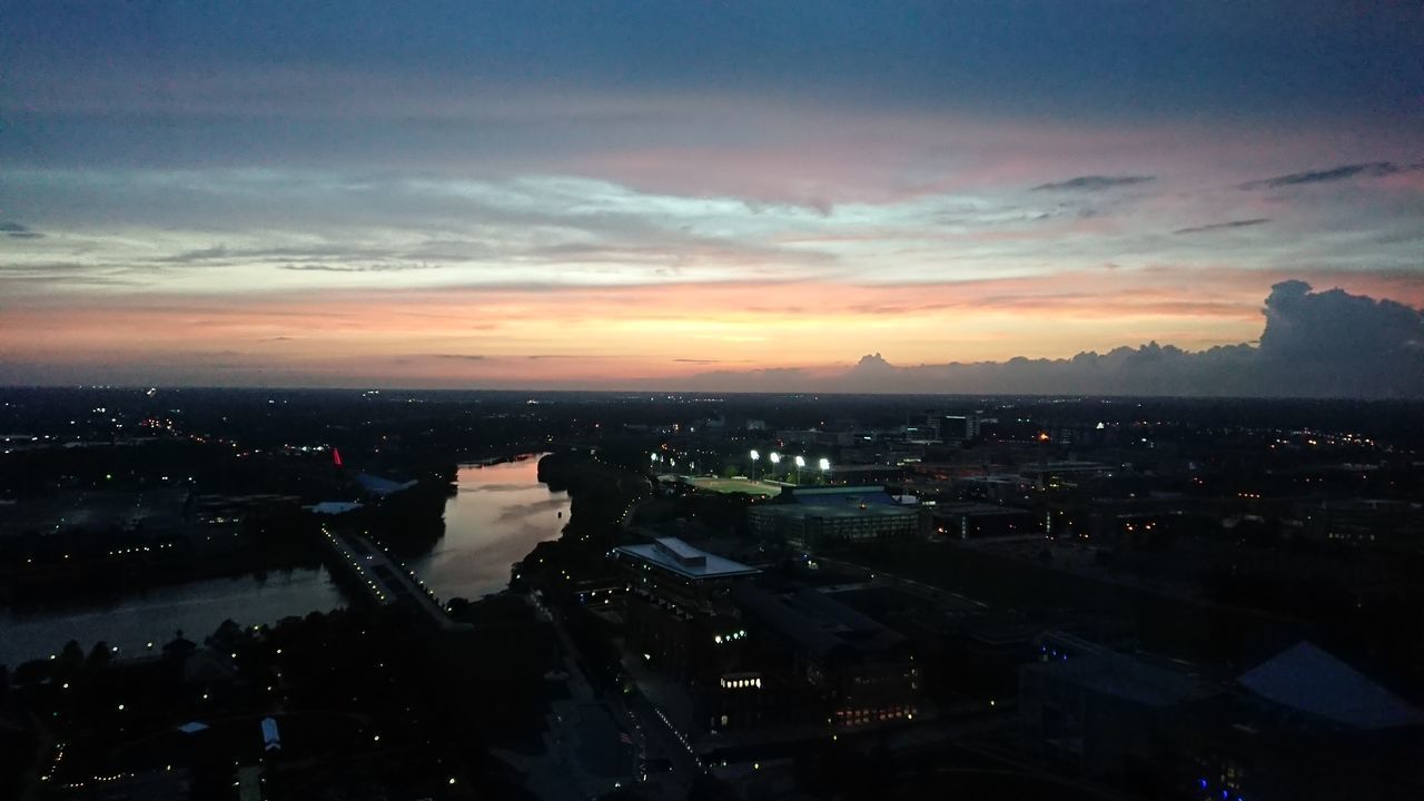 HIGH ANGLE VIEW OF ILLUMINATED BUILDINGS IN CITY AT SUNSET