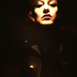 Close-up of young woman against black background