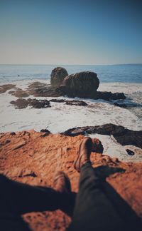 Low section of rocks on beach against clear sky