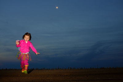 Full length of girl in butterfly costume running on field at dusk