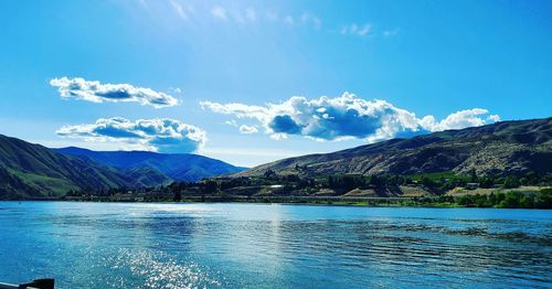 Scenic view of river and mountains against blue sky