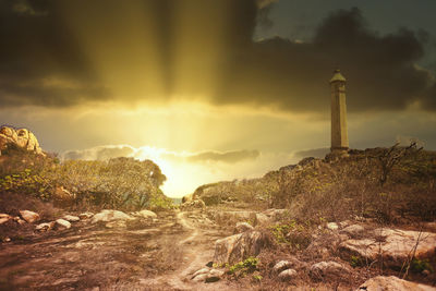 Lighthouse amidst buildings against sky during sunset